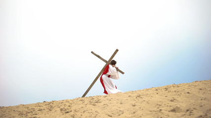 Historical personification of Jesus Christ carrying wooden cross, crucifixion