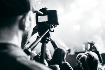 Videographer with camera filming concert on video at night