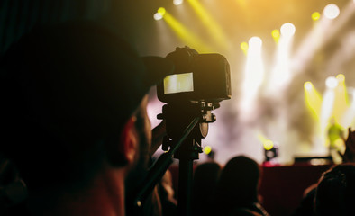 Videographer with camera filming concert on video at night