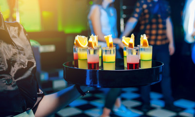 The waiter holds a tray with set of shots in the club