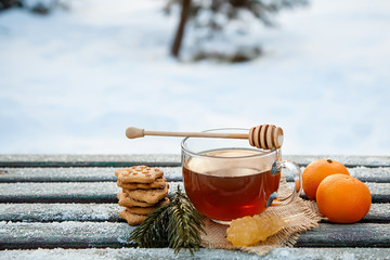 Cup of hot tea witn honey , tangerines and cookies in the winter forest. the concept of Christmas...