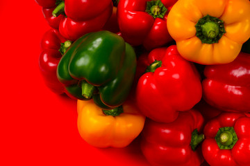 Fresh red, yelow, green bell pepper on a red background.