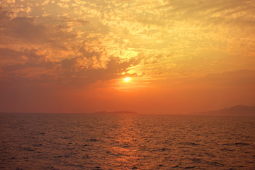 Beautiful sunset over Aegean sea with some clouds and golden colours