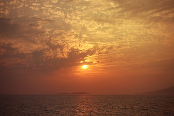 Beautiful sunset over Aegean sea with some clouds and golden colours