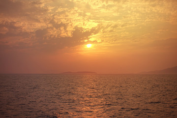 Fototapeta premium Beautiful sunset over Aegean sea with some clouds and golden colours
