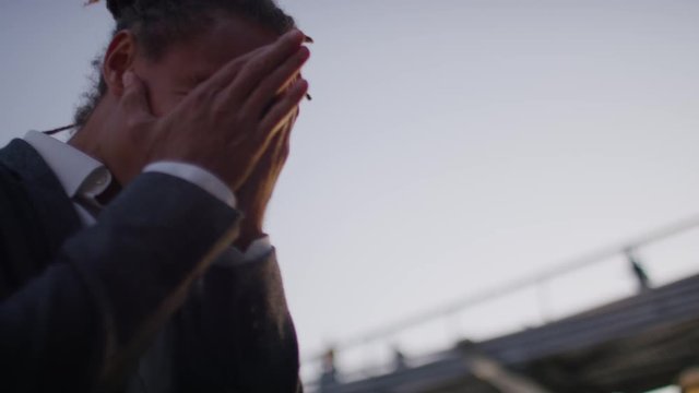Business professional received bad news on his phone and puts his head in his hands