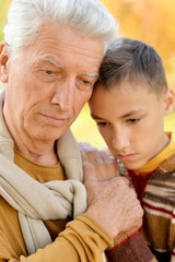 Close up portrait of sad grandfather and grandson hugging