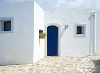 Detail of a typical greek building with white walls and blue door