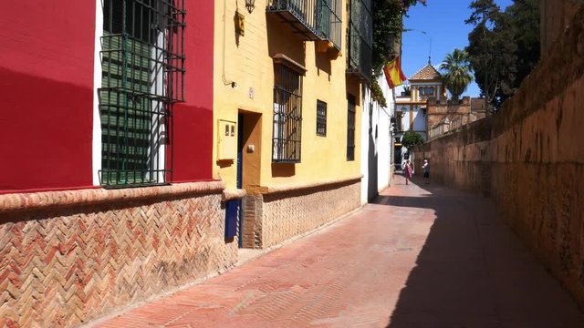 POV walking down old picturesque passageway in the medieval Jewish Quarter of Santa Cruz in Seville, Andalusia, Spain