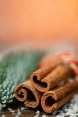 Cinnamon and christmas decoration on wooden table. Spruce branch and snow. Morning in the bright living room. Holiday mood.