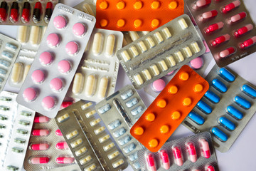 A pile of pills in blister packs. Blister packs full of multi-colored pills. Close-up on a light background. Full colored pills package. Pharmaceutical blister pack. Pack of pills with tablets.