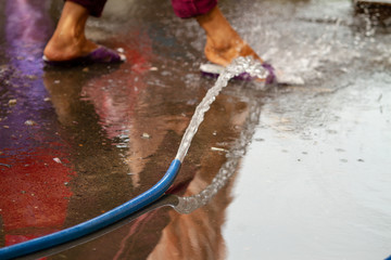 Woman cleaning feet with hose on street, Vietnam