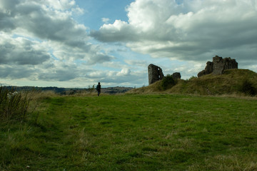 Ruins and hiker at green field