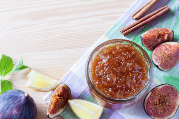 Whole and cut figs, with dish of homemade fig jam or marmalade kitchen wooden table with copy space.