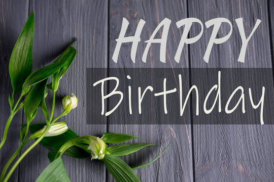 Greeting card with the inscription happy birthday. Congratulatory greeting to the girl, mother with flowers and a gift on a wooden background. Alstroemeria flowers