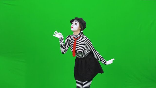 Mime girl has found dandelion, blowing on it. Chroma key.