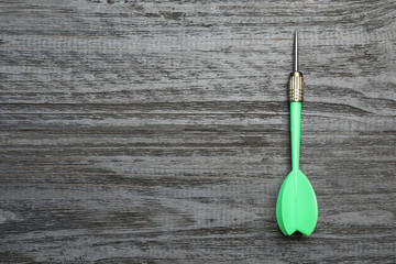 Green dart arrow on grey wooden table, top view with space for text