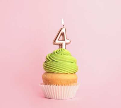 Birthday cupcake with number four candle on pink background