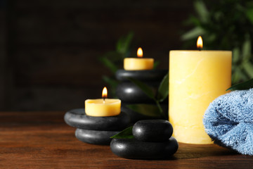 Composition with candles and spa stones on wooden table. Space for text