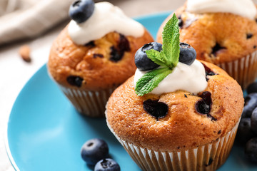 Plate of tasty muffins and blueberries on table, closeup