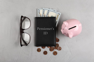 Pension certificate with American money, glasses and piggybank on grey stone table, flat lay