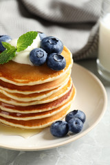 Plate of tasty pancakes with blueberries, sauce and mint on table, closeup