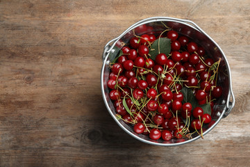 Bucket of delicious cherries on wooden table, top view. Space for text