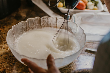 woman with blender mixing ingredients for pastry in traditional kitchen