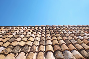 View of old roof tiles and blue sky on sunny day