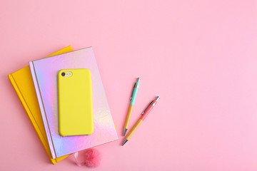 Smartphone, notebooks and pens on pink background, flat lay