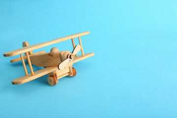 Wooden toy plane on blue background. Space for text