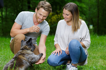 young couple petting dog outdoors