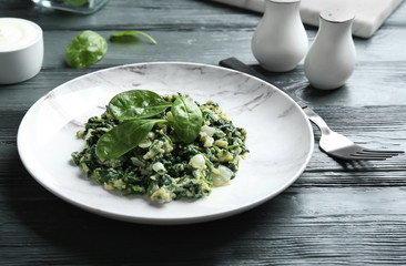 Tasty cooked spinach served on dark wooden table. Healthy food