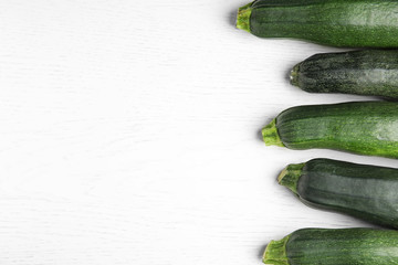 Fresh ripe green zucchinis on white wooden table, flat lay. Space for text