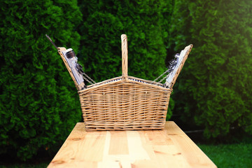 Fototapeta na wymiar Wicker picnic basket on wooden table in park