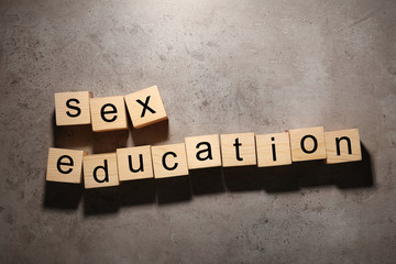 Wooden blocks with phrase "SEX EDUCATION" on stone background, flat lay