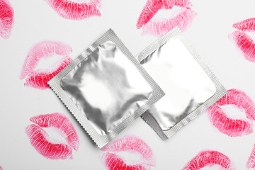 Condoms and lipstick kiss marks on white background, top view. Safe sex