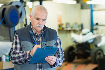 Fototapeta premium elderly mechanic checking quad vehicle