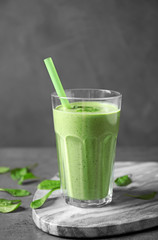 Glass of healthy green smoothie with fresh spinach on grey table