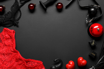 Frame made with different sex toys and Christmas balls on black background, flat lay. Space for text
