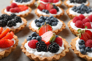 Many different berry tarts on table. Delicious pastries