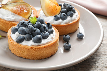Plate of tarts with blueberries and figs on wooden table, closeup. Delicious pastries