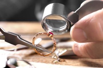 Male jeweler examining ruby ring in workshop, closeup view - obrazy, fototapety, plakaty