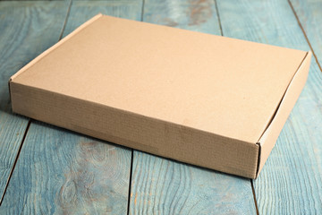 Closed cardboard box on light blue wooden table