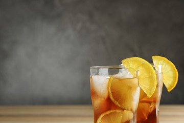 Glasses of tasty ice tea with lemon on grey background, space for text