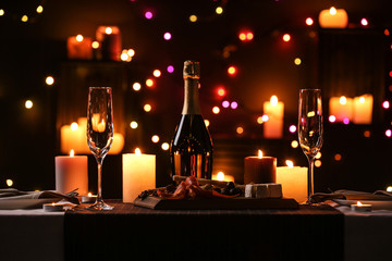 Romantic dinner table setting with burning candles and festive lights