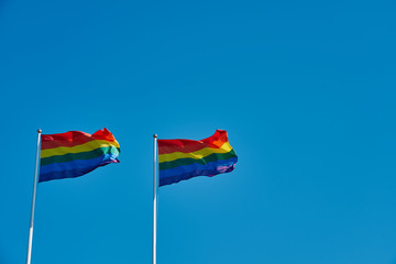 Rainbow flags against a clear blue sky. Copy space.