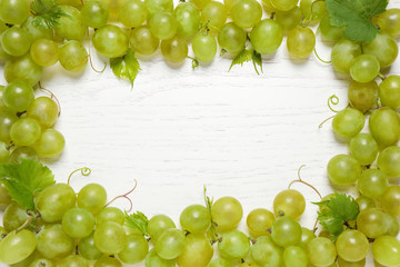 Frame made with fresh ripe juicy grapes on white wooden table, space for text