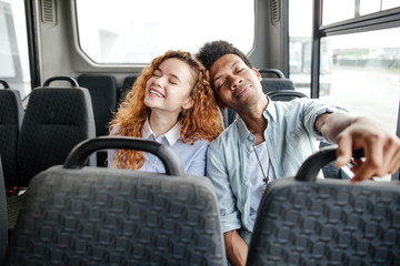 Young couple leaning their heads sitting on the bus going through the city