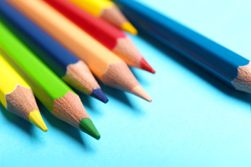Colorful pencils on light blue background, closeup